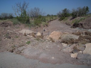 The flood keeps trying to wash out his paving. He pounded steel posts into the wash to hold boulders to try and slow the water down, so that it will deposit its silt instead of just gaining speed on the paving and digging it out more on the downstream side. It's slowly failing because the wash always wins in the end, but I admire his perseverance. 